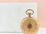 an image of a gold pocket watch sitting on top of a marble block