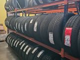 tires are stacked on a rack in a warehouse with a yellow wall in the background