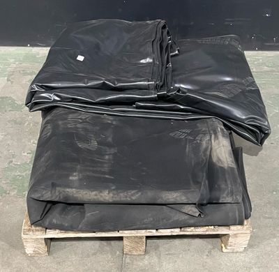 une pile de bâches noires posée sur une palette en bois