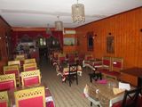 many tables and chairs in this restaurant with a chandelier hanging from the ceiling