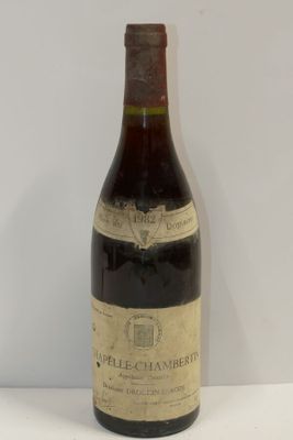 une vieille bouteille de vin posée sur une table blanche