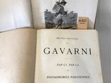 un livre ouvert posé sur une table blanche, à côté d'une pile de livres