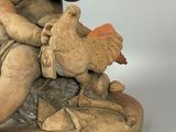 a statue of a man sitting on a rock with a bird