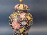 un vase noir et doré orné de fleurs sur fond bleu