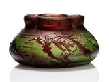 un vase vert et rouge posé sur une surface blanche
