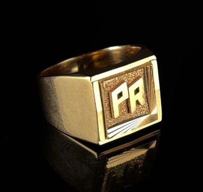 a close up of a gold signet ring on a black surface