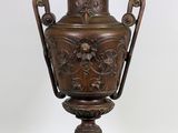 une image représentant une grande urne en bronze posée sur un socle en bois