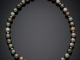 a black pearl necklace with a gold clasp on a black background