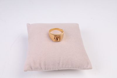 bague en or jaune posée sur un coussin, sur fond blanc