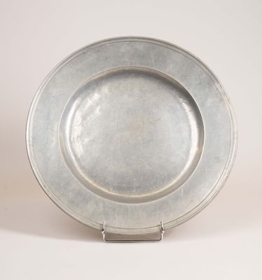 a silver plate on a metal stand on a white surface