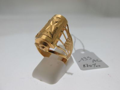 une image d'une bague en or sur une surface blanche avec une étiquette de prix