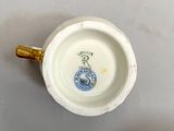 a white cup with a gold handle sitting on a table