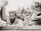 several soldiers are sitting on the side of a truck with a man with a beard