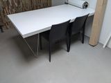 a white table with two black chairs in front of a brick wall