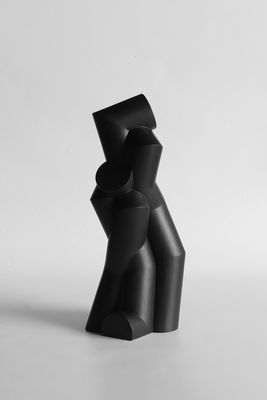 une sculpture noire posée sur une table près d'un mur blanc