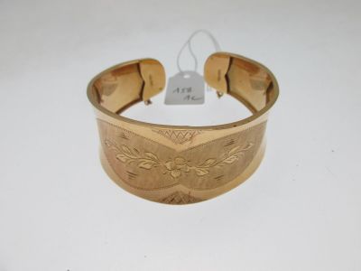 gros plan d'un bracelet en or sur une surface blanche
