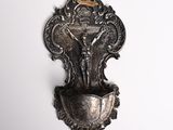 a wall mounted silver plate with a crucifix on it