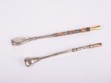 two silver spoons and a spoon with a handle on a white surface