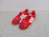 baskets Adidas rouges avec des bandes blanches sur les semelles