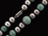 a close up of a necklace on a black surface with a silver clasp