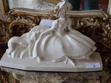 a statue of a woman sitting on a table in front of a mirror