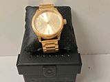 michael korsch gold watch on a black box with a white background