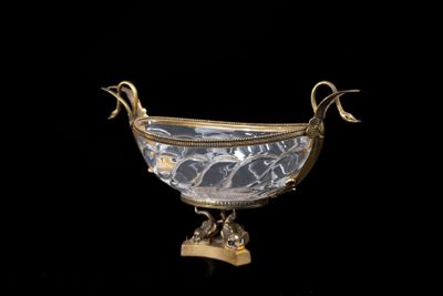 a silver and gold bowl on a stand on a black background