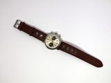 an image of a watch on a white surface with a brown strap