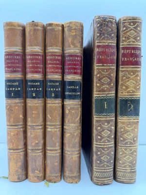 six vieux livres sont alignés sur une surface blanche