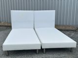 a pair of white leather chaise loungers in a parking lot