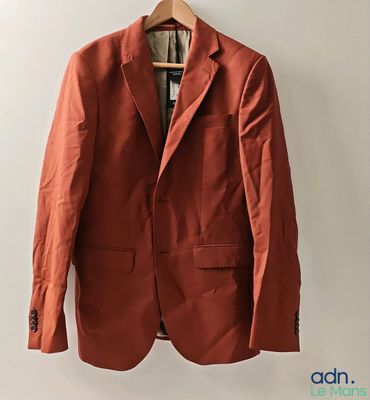 un blazer orange suspendu à un cintre accroché au mur