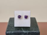 une paire de boucles d'oreilles en améthorate posées sur un bloc de marbre