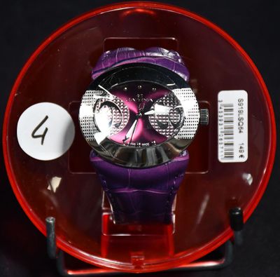 une montre violette dans un écrin rouge posée sur une surface noire