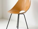 a wooden chair with black legs in a white room