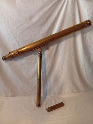 un télescope en laiton sur fond blanc, avec une bouteille