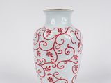 un vase blanc orné d'un motif rouge