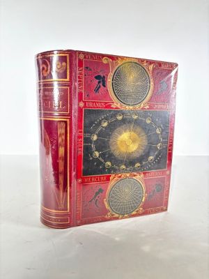 an old red book with a clock on it sitting on top of a table