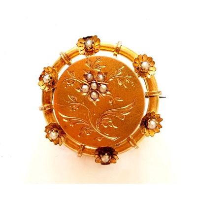 une image représentant une broche en or ornée de perles