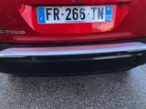 the rear end of a red car with a number plate on it