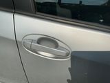 a silver car with a door handle on the side of the road