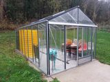 une serre en verre avec une table et des chaises à l'intérieur