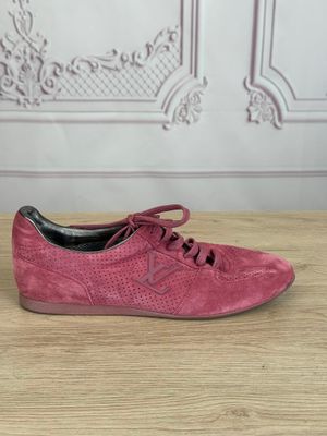 Les baskets en daim rose sont posées sur une table en bois.