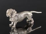 une figurine en argent représentant un chien posée sur une surface réfléchissante