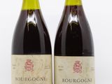 two bottles of red wine sitting next to each other on a white surface