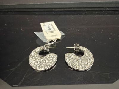 une paire de boucles d'oreilles argentées et en cristal exposées dans une vitrine