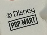 a close up of a toy bear with a disney pop mart sticker on it