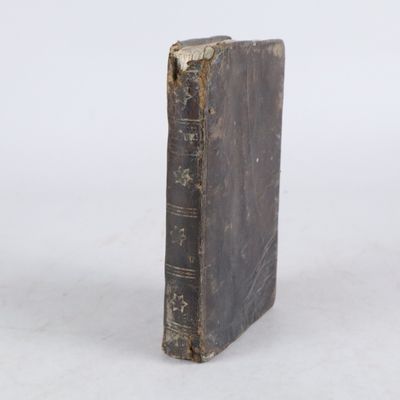un vieux livre posé sur une table à côté d'un mur blanc