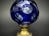un vase en verre bleu avec un socle doré posé sur une table