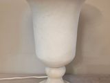 un vase blanc posé sur une table, auquel est attaché un cordon