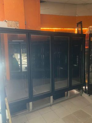 a row of black refrigerators in a room with orange walls